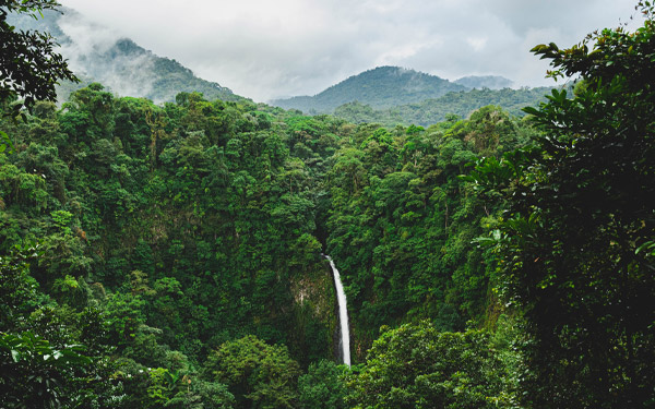 waterfall in the jungle with mountains and clouds in the background