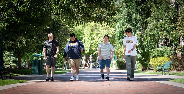 Four global students walk together on campus