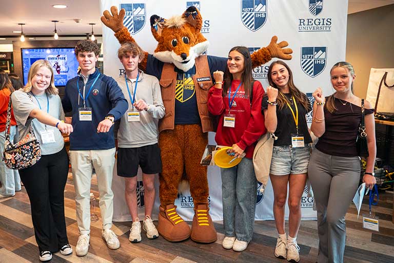 a group of first-year students pose with Regis the mascot in the Student Center on the Regis Denver Campus