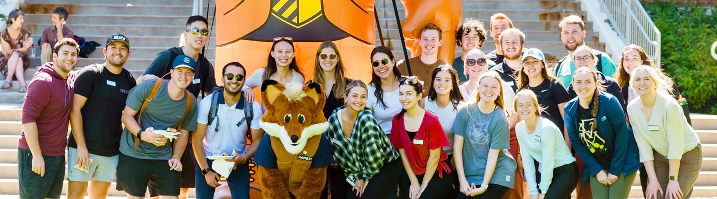 Crowds of students poses with Regi the Fox for a group photo at Blue and Gold Weekend on the Northwest Denver campus