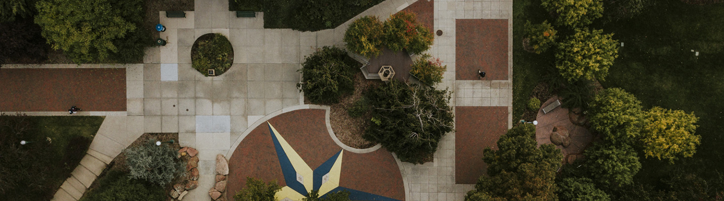 compass on pavement outside Carroll Hall