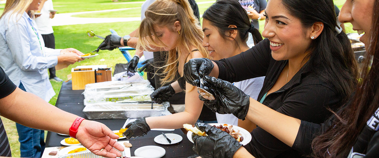 Regis students serve arepas during a Comidas event on the quad on the Regis University campus