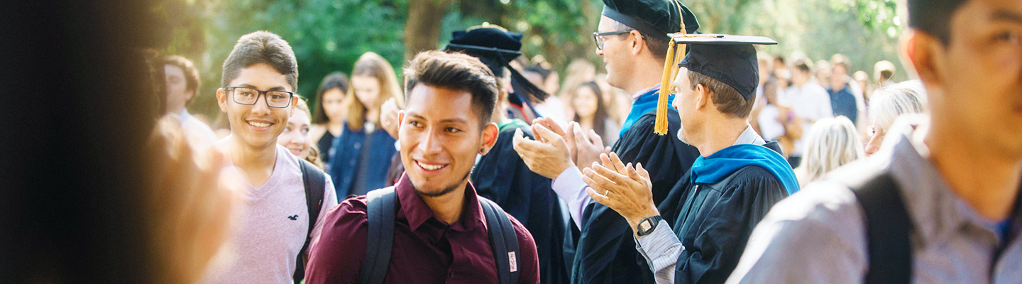 students smile as they process pass professors during the convocation ceremony