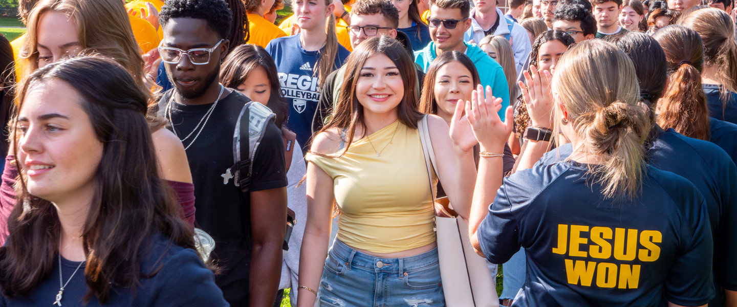 Regis University students walking together and greeting each other on campus