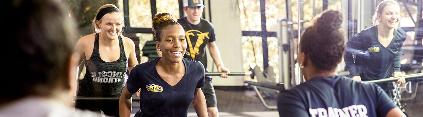 a Regis Health and Exercise Science student leads a strength training class for her fellow students in the fitness center