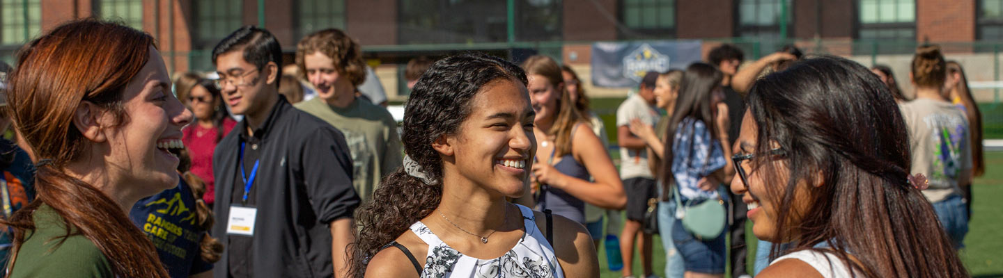 Students smiling together while standing on the Regis soccer field