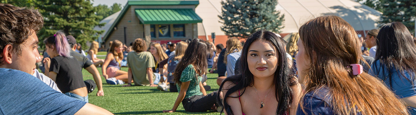 students sit on the grass in discussion circles during the Playfair icebreaker during new student orientation on the northwest denver campus