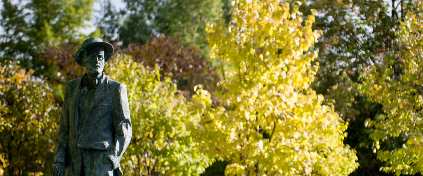 Statue on the Regis University campus lawn with trees showing fall foliage.