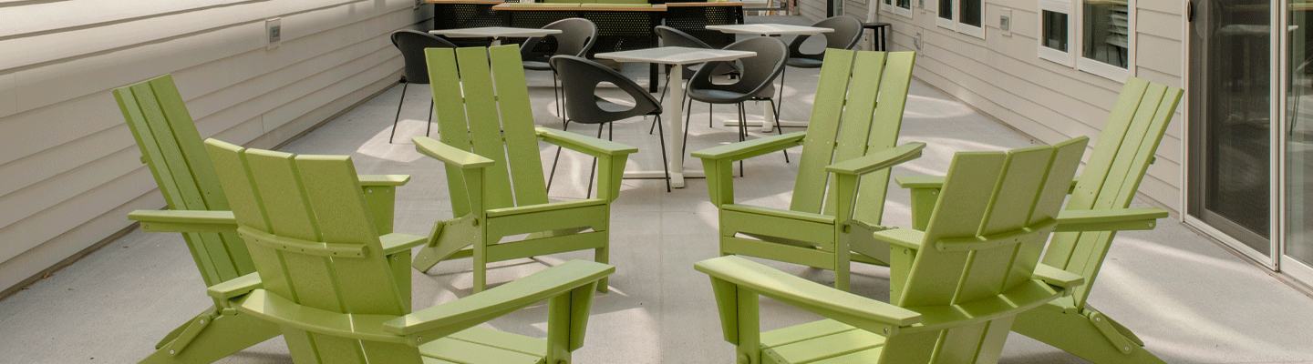Inviting adirondack chairs arranged in a circle on a cozy patio with a grilling station in the background