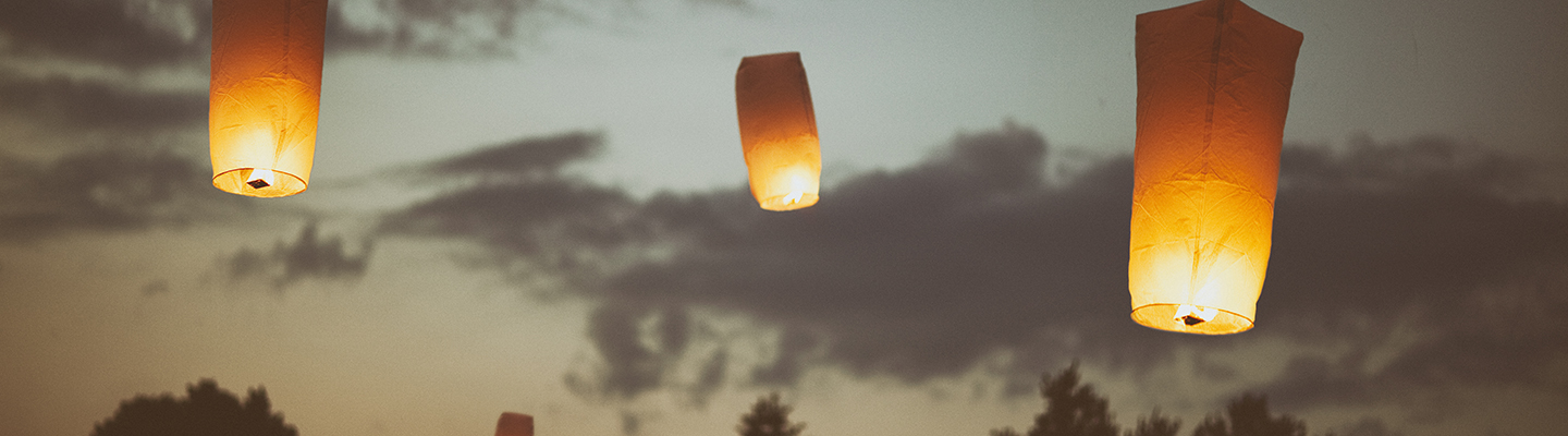 paper memorial lanterns floating in evening sky