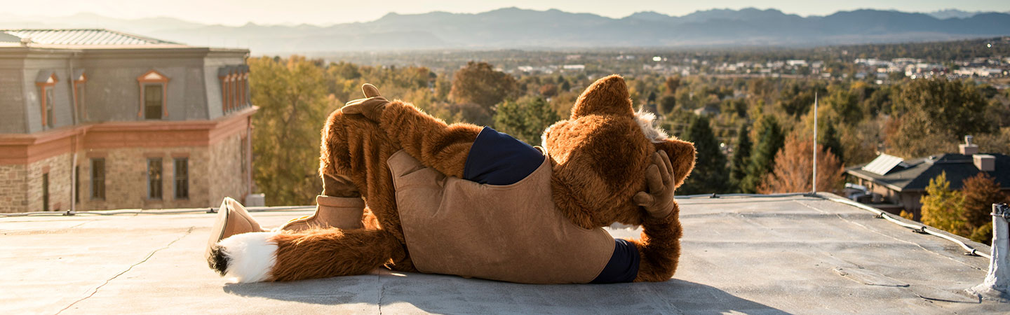 Regi posing on top of Main Hall looking towards the mountains