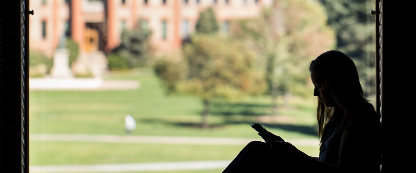 student sitting in a nook in the library with a view