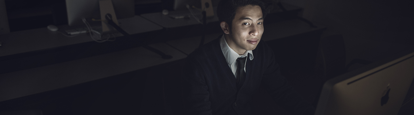 student in dark room on computer
