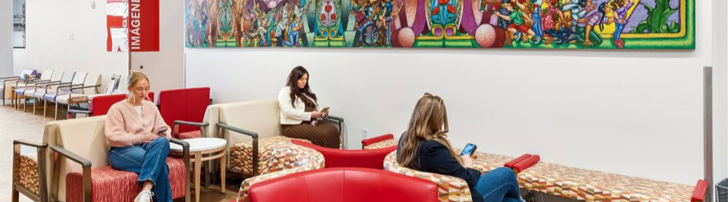 Three people sit in a waiting room looking down at their phones in different chairs
