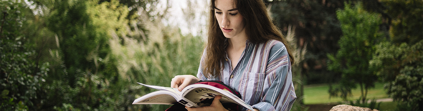 female student reading outside in arboretum