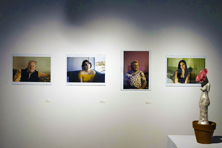 framed portrait photos on display in a gallery beside a sculpture