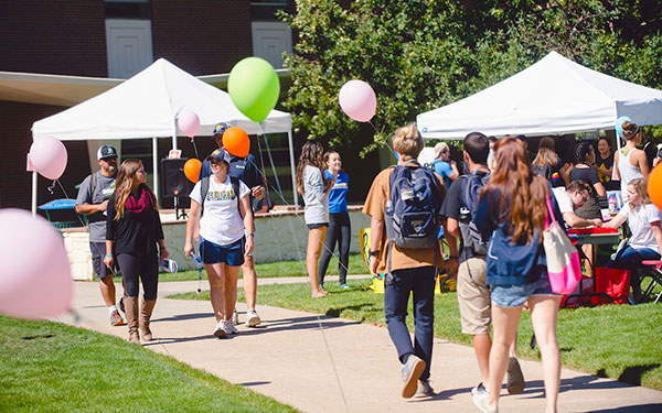 a crowd of prospective students gathers among tents and balloons on Boettcher Commons for an outdoor Admissions event.