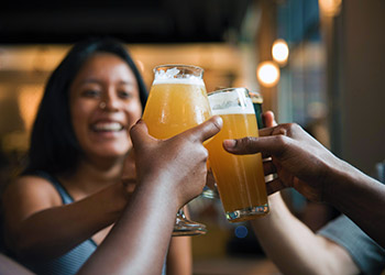 adults toast with full beer glasses at a brewery
