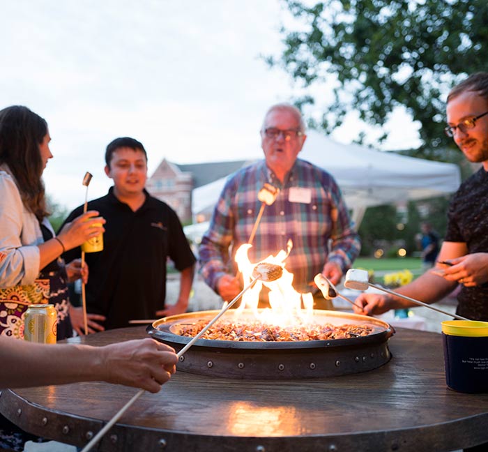 Regis alumni roasting marshmellows