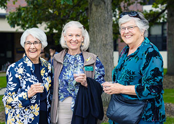three alumni pose for a photo on the quad