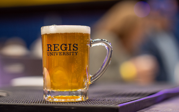close-up of beer glass with an illustration reading "Regis University"