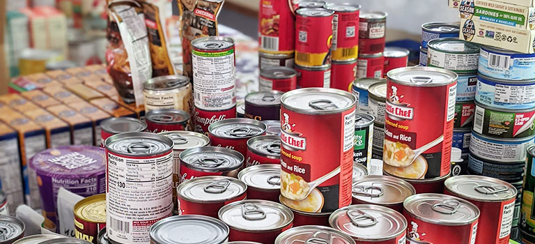 piles of non-perishable food in cans, boxes and cartons stacked in a room