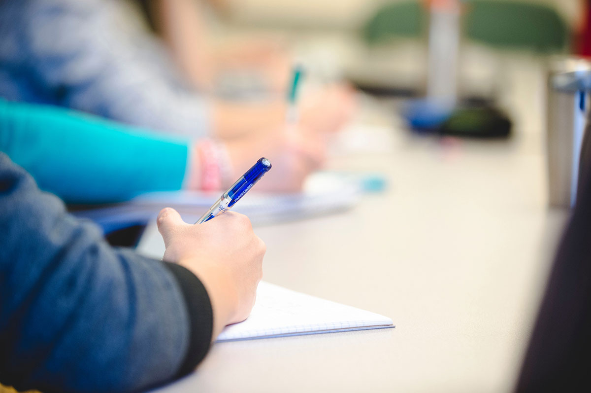 students in a Regis classroom writing an assignment with pen and paper