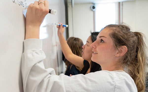 Students writing on a board in class