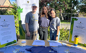 students pose for a photo while working the SEED table at Climate Action Day outside the Chapel on the Regis campus