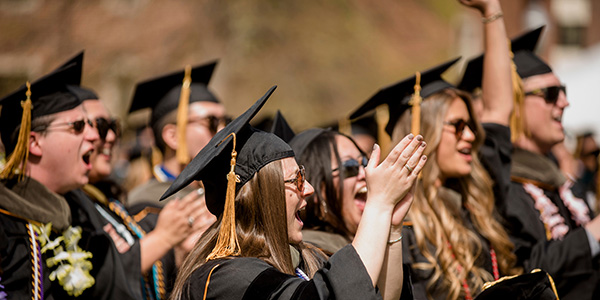 Graduates in regalia clap and cheer at commencement on Boettcher Commons on the Northwest Denver Campus