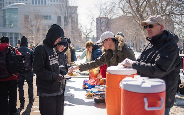 Regis University students and volunteers serving food during a community outreach event.