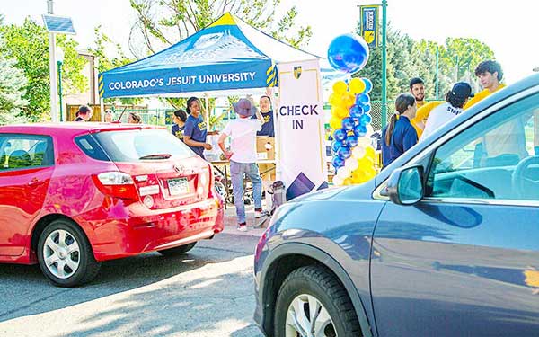 students drive up to the check-in tent where staff wait to welcome them to the annual commuter student orientation event on campus
