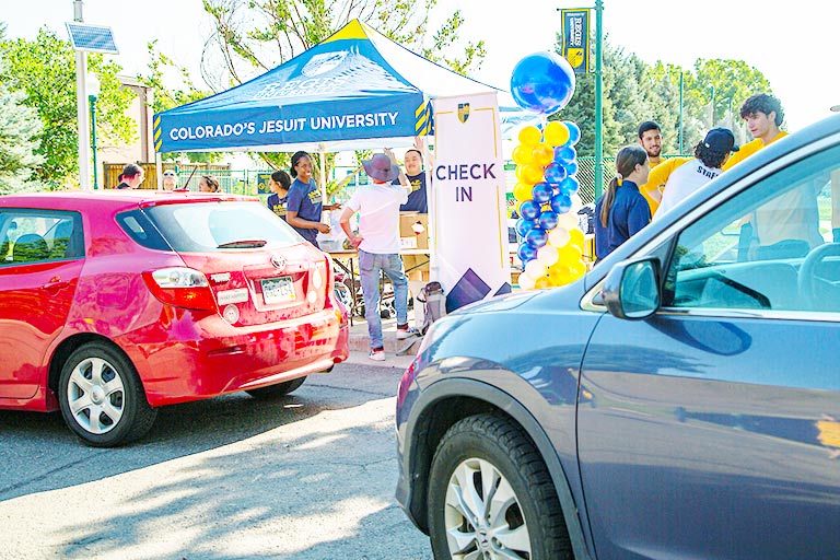 cars pull up to a check-in tent during Commuter Connect on the Regis campus