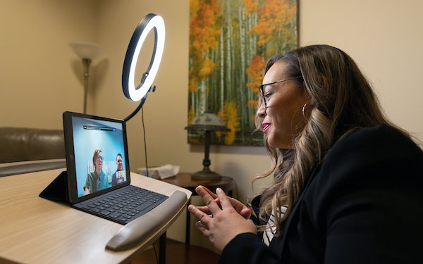 a therapist talks to teletherapy patients on a laptop at the Center for Counseling, Family and Play in Thornton