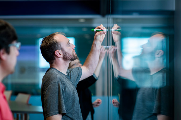Anderson student writing on a glass board
