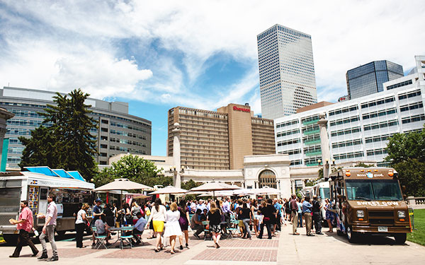 a crowd of people gathers under umbrellas and waiting in line for food trucks in downtown Denver