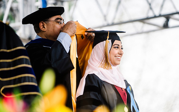 member of faculty bestows doctoral hood on graduate at commencement