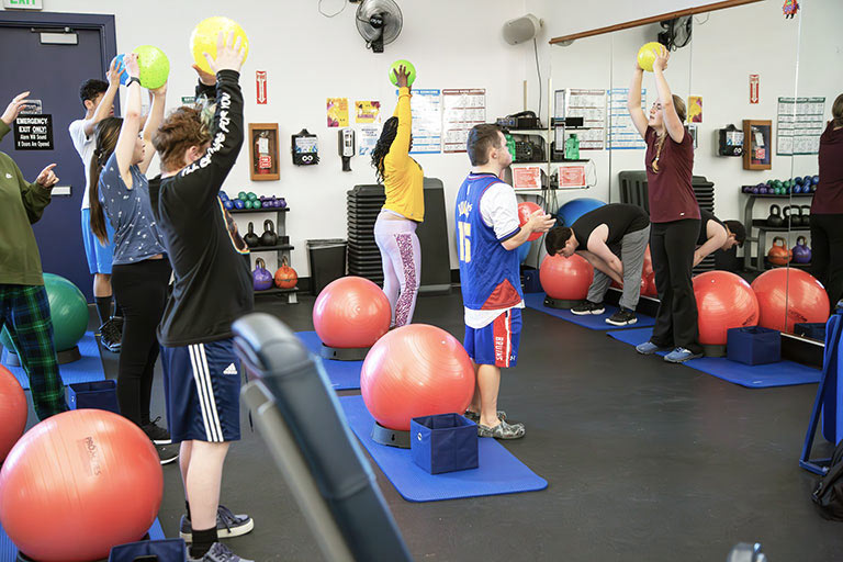  a student in the doctor of physical therapy (DPT) program leads a group of students through physical therapy exercises using balls and mats in the PT lab on the Denver, CO, campus