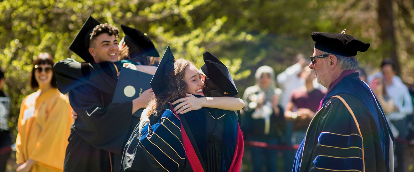 graduates and faculty embrace during commencement