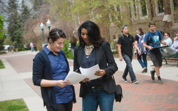 faculty reviews paper with student outside