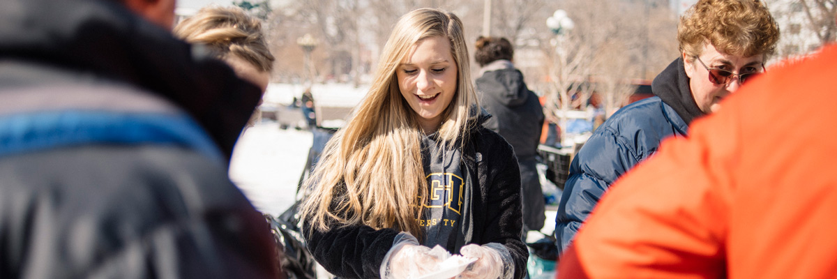 Regis University student volunteering at an outdoor campus event, serving food in a snowy setting
