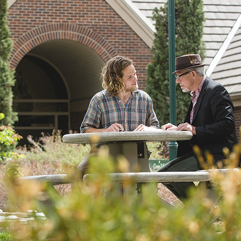 two adult undergraduates students smile outside library