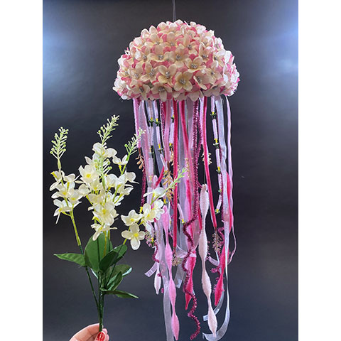 photo of a sculpture suspended in space with flowers and long tendrils hanging down