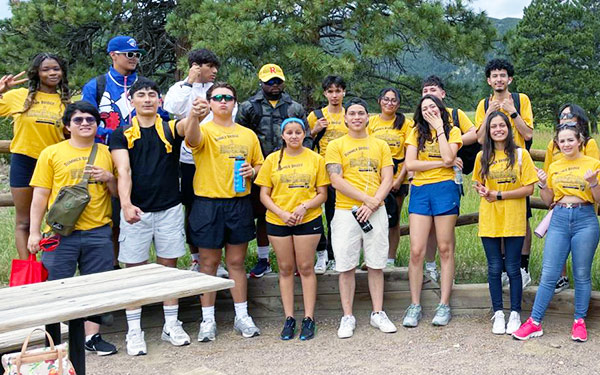 a group of first-gen students wearing matching t-shirts poses for a photo before beginning an outdoor activity