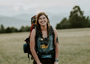 student smiling with large camping backpack