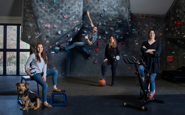 Students and staff climbing on and around a rock climbing wall