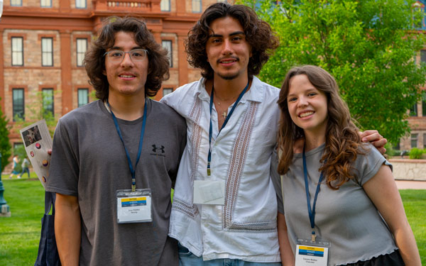 Three prospective students pose together for a small group photo and smile and the camera