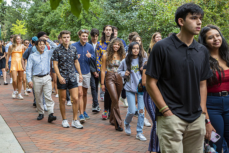 a large group of first-year students walks along the Quad
