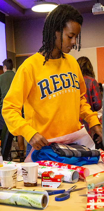 Regis student gift wrapping toys and clothing during a holiday gift drive.