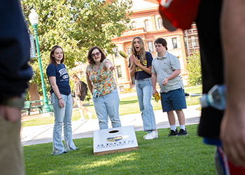 Global students stand together playing cornhole/bags